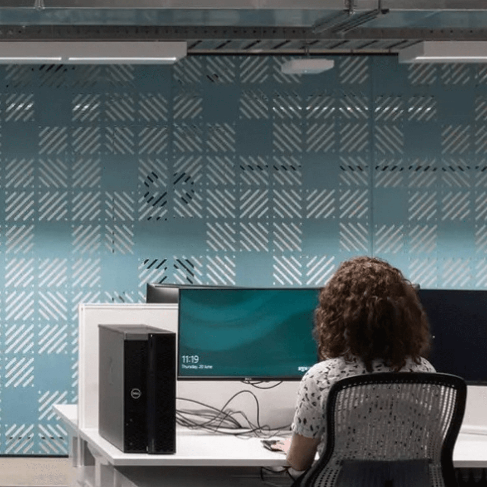 Woman at a desk in a modern workspace featuring acoustic panels designed for soundproofing and improved focus.