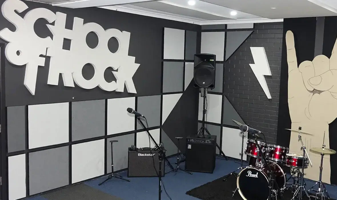 Vibrant music studio with 'School of Rock' sign, equipped with drums and amplifiers for creative audio production.