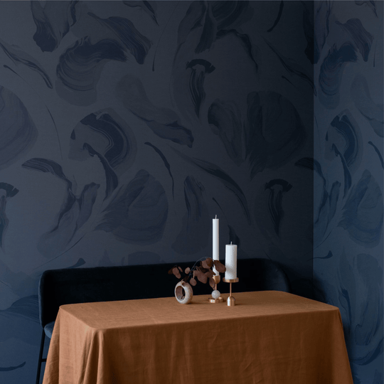 Cozy dining setup featuring navy patterned walls, an orange tablecloth, and decorative candles.