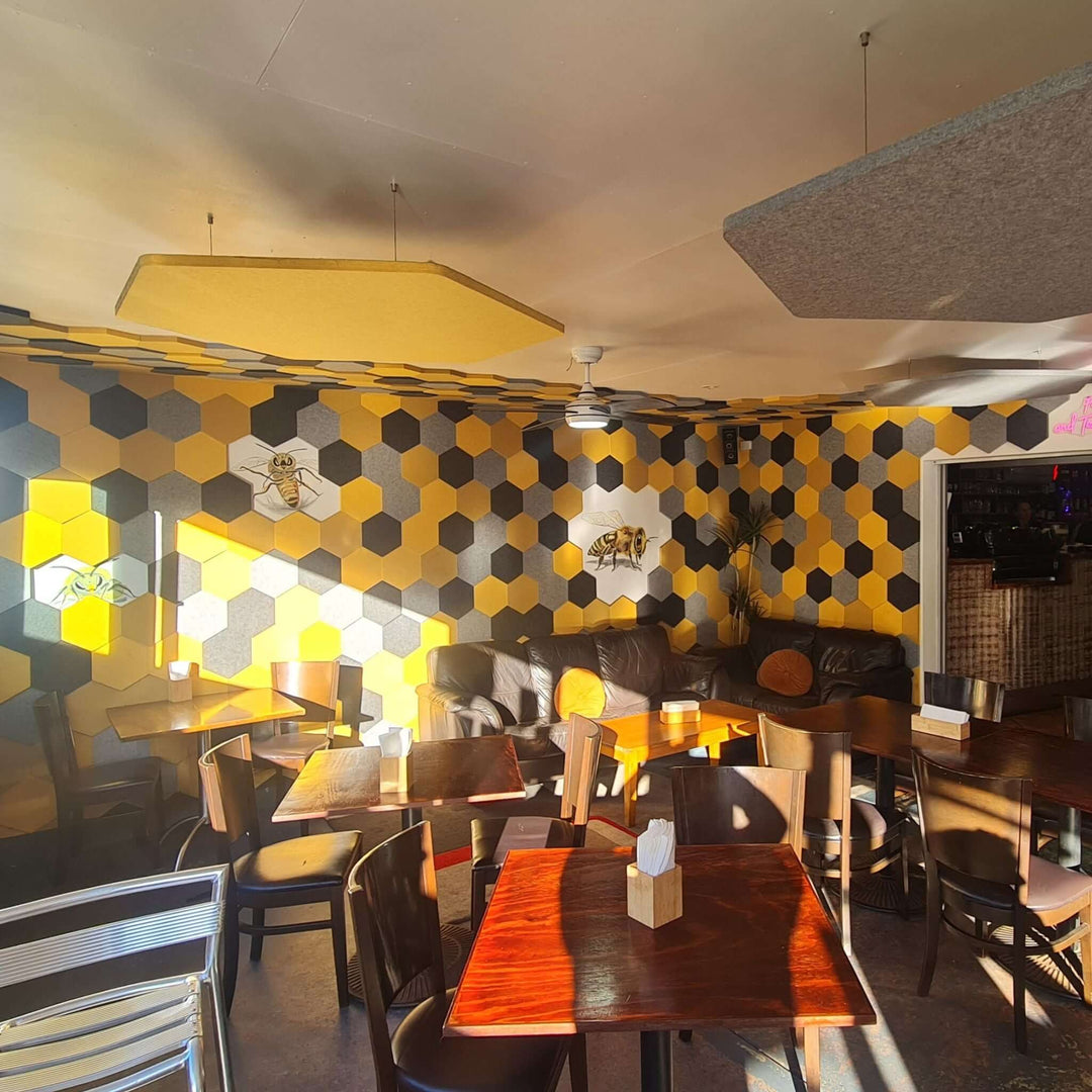 Interior of a cafe featuring yellow and black honeycomb wall design with Autex Cube Honeycomb Acoustic Tiles.