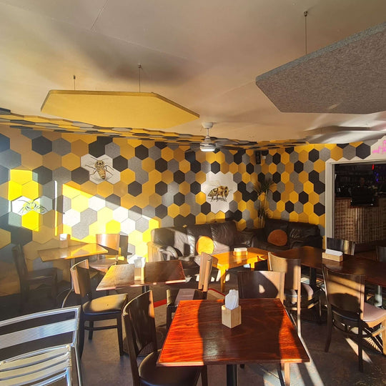 Interior of a cafe featuring yellow and black honeycomb wall design with Autex Cube Honeycomb Acoustic Tiles.