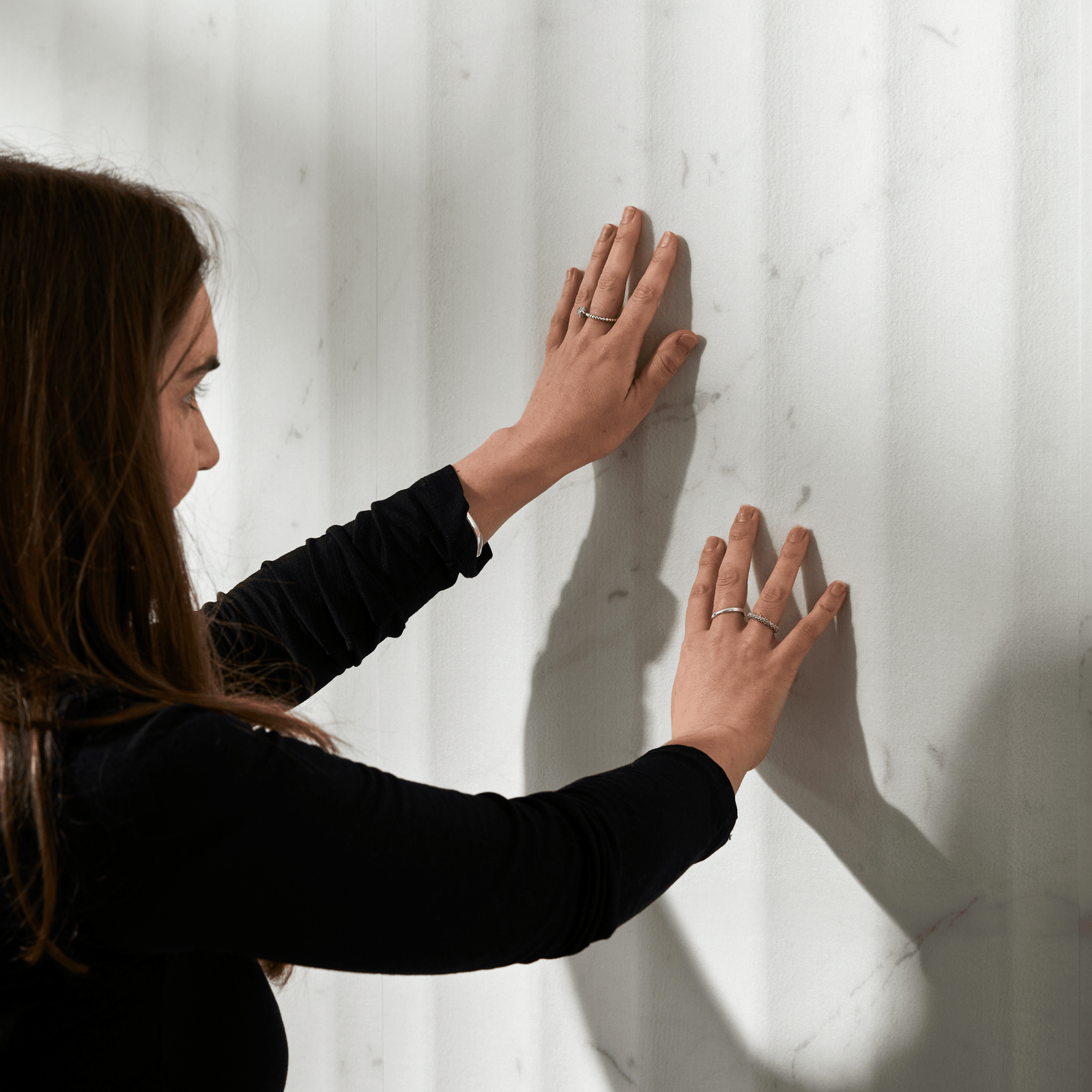 Person touching textured acoustic wall panels to show the surface finish and design detail