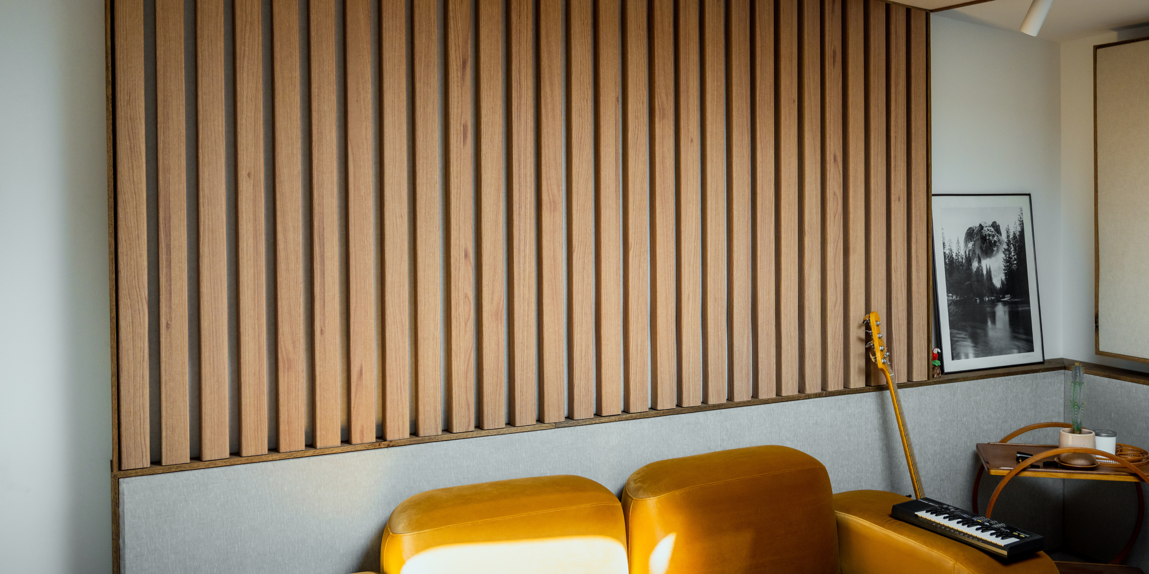 Modern office space featuring acoustic timber panels, stylish chairs, and a glass partition for soundproofing.