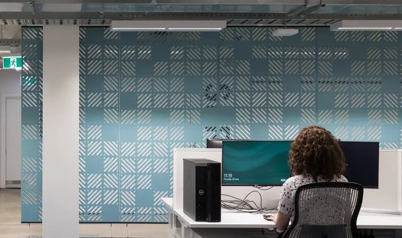 Woman working at a desk with Cascade™ acoustic panels for soundproofing and stylish office privacy.