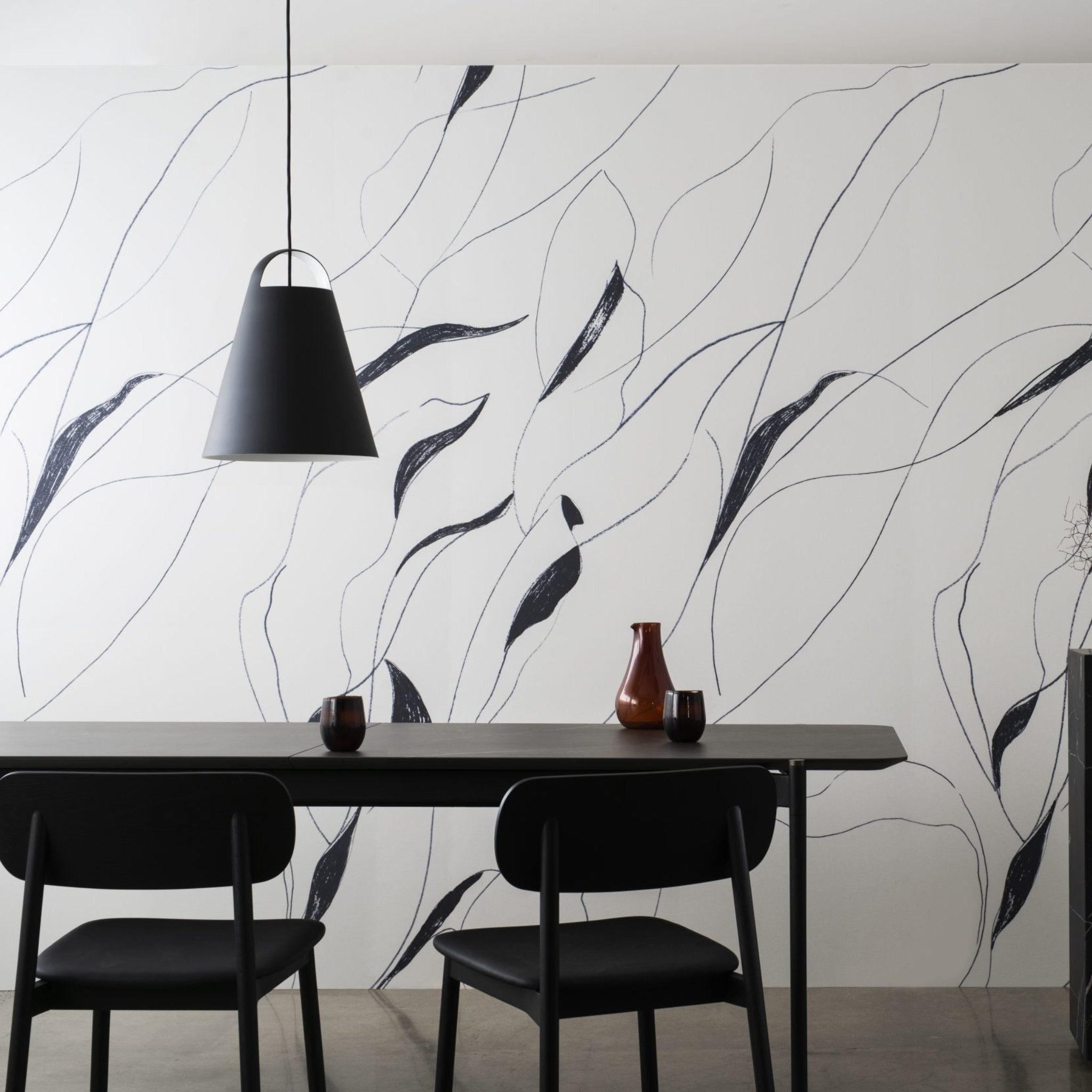 Black and white abstract leaves wallpaper enhances modern dining space with stylish table and pendant light.