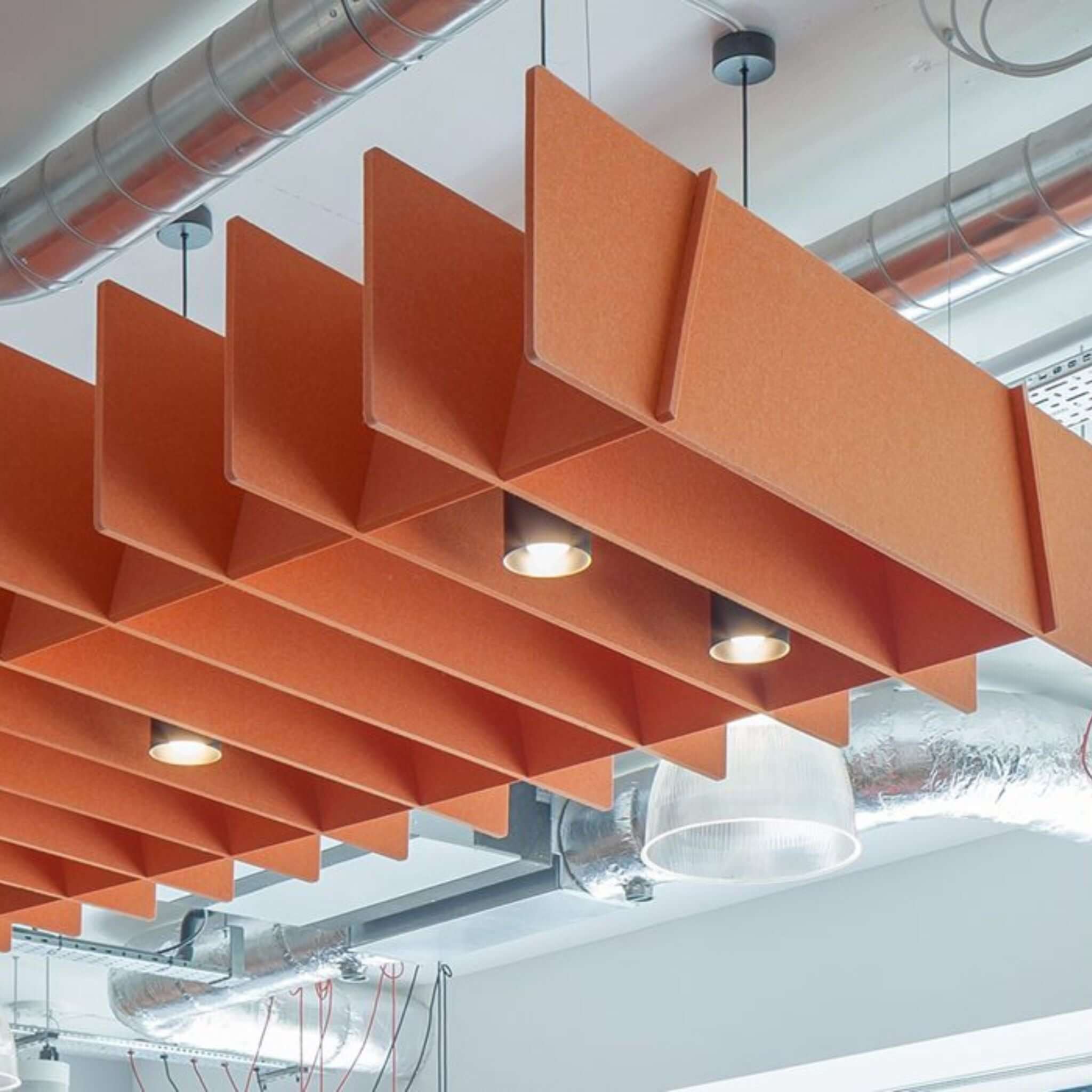 Acoustic panels in orange design suspended from ceiling, enhancing soundproofing for modern spaces.