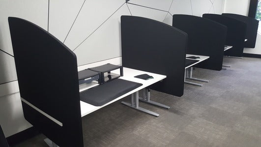 Modern office setup with black desk dividers creating private workspaces for enhanced focus and soundproofing.