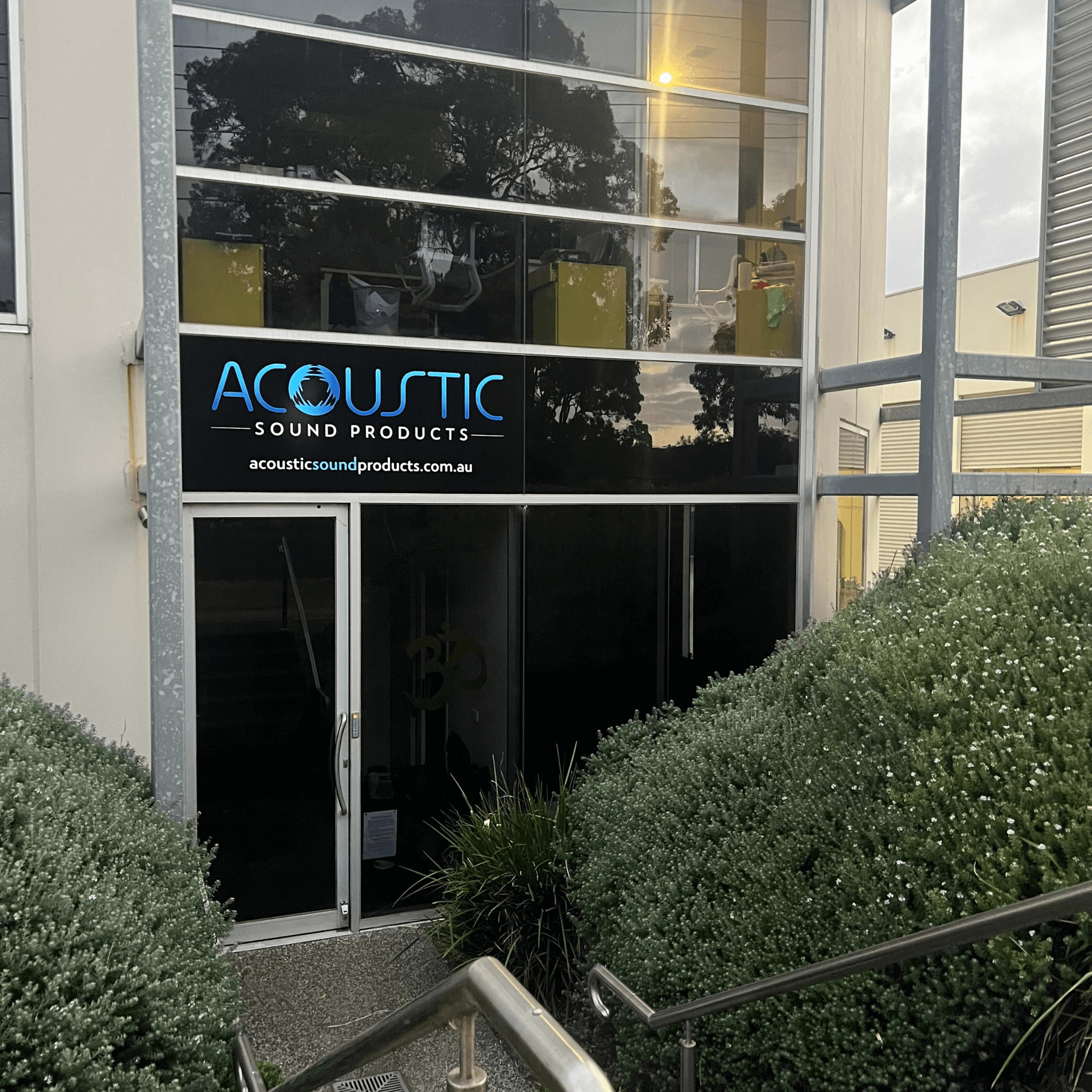 Entrance to Acoustic Sound Products, showcasing the brand's sign and greenery.