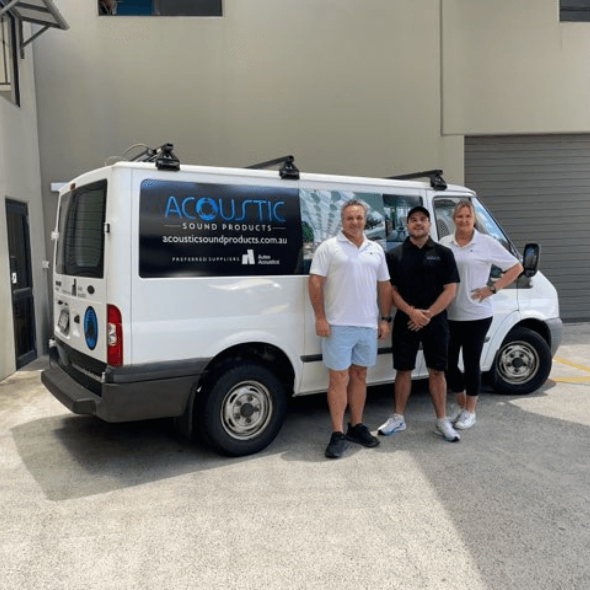 Team from Acoustic Sound Products standing beside their branded van in front of a warehouse, promoting sound solutions.