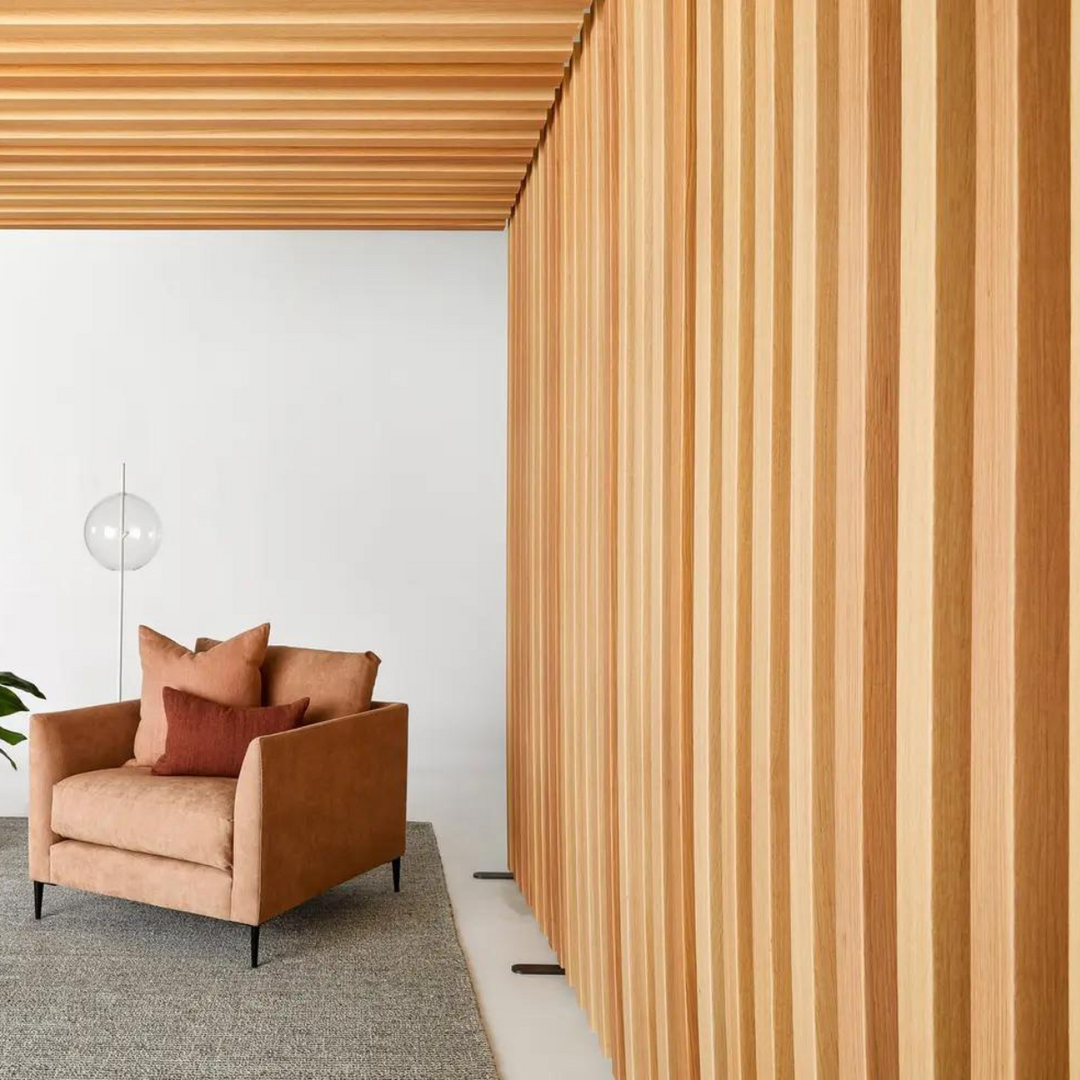 Contemporary living space featuring a tan armchair and stylish wooden panelled wall with a modern lamp.