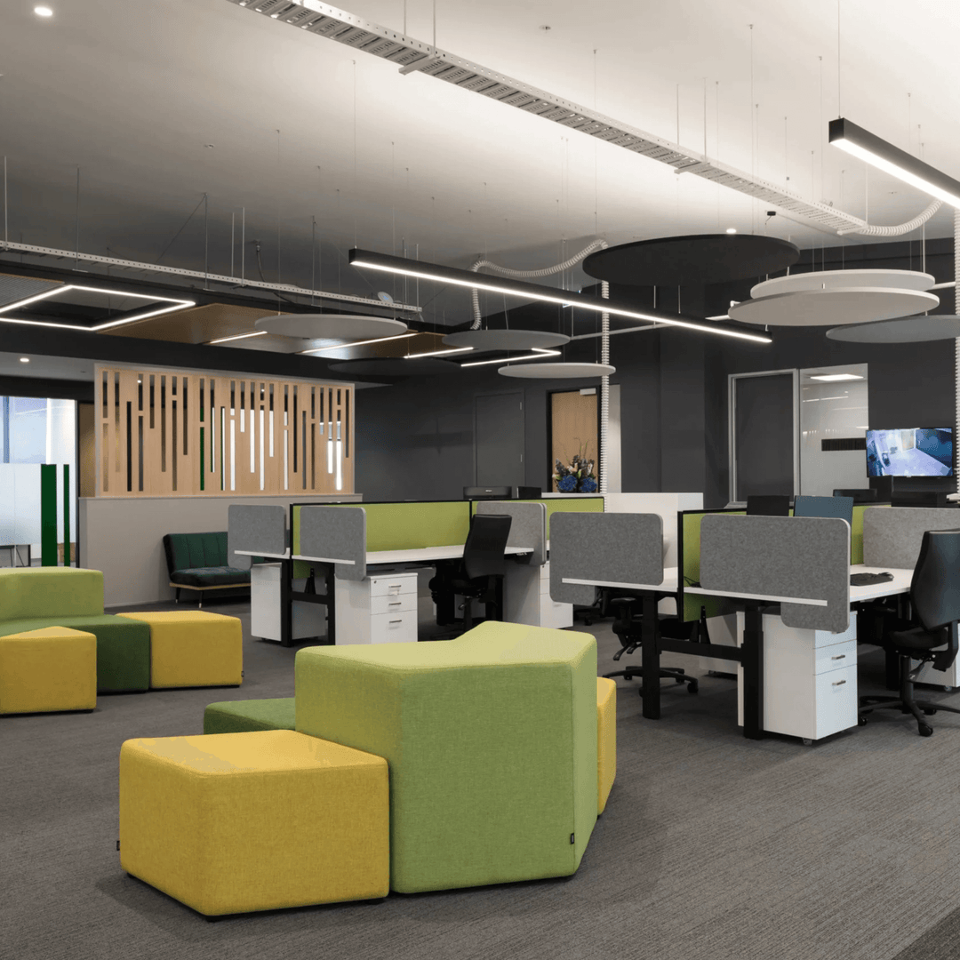 Modern open-plan office featuring Autex Cove desk dividers, green and yellow seating, and sleek, acoustic design elements.