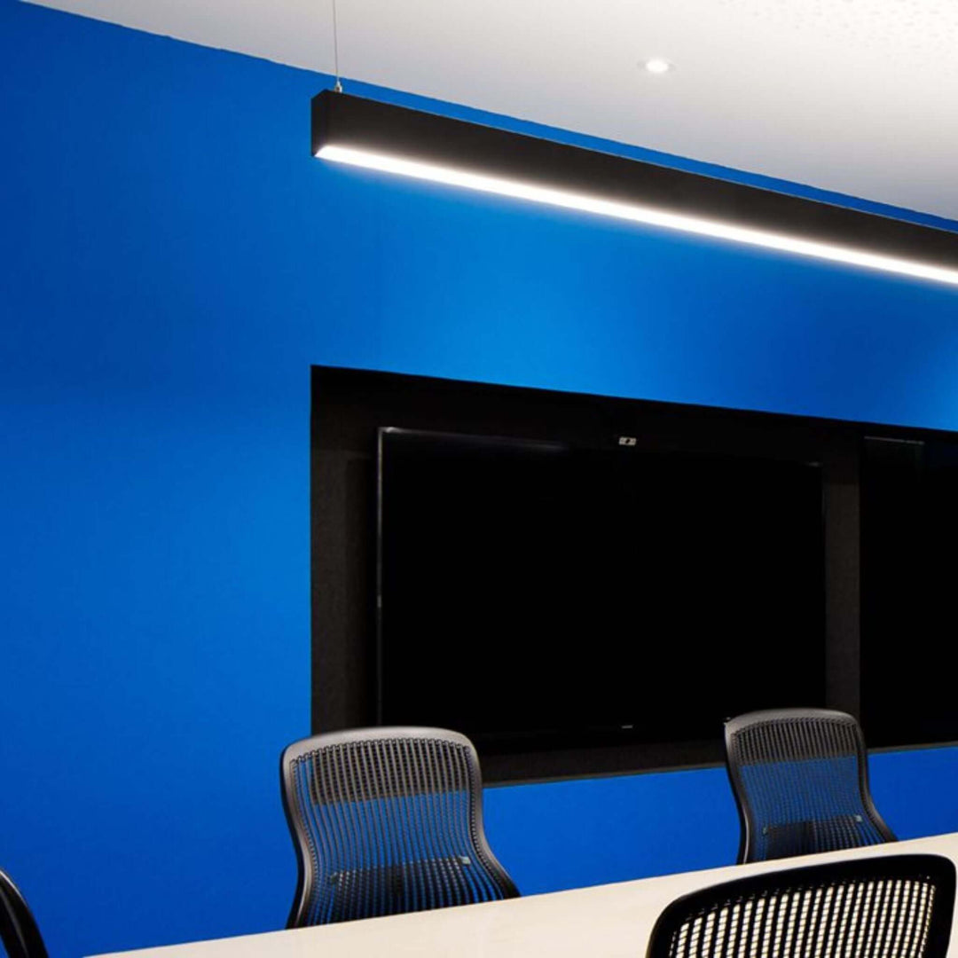 Modern conference room with blue acoustic wallcovering and sleek lighting above a TV screen and chairs.