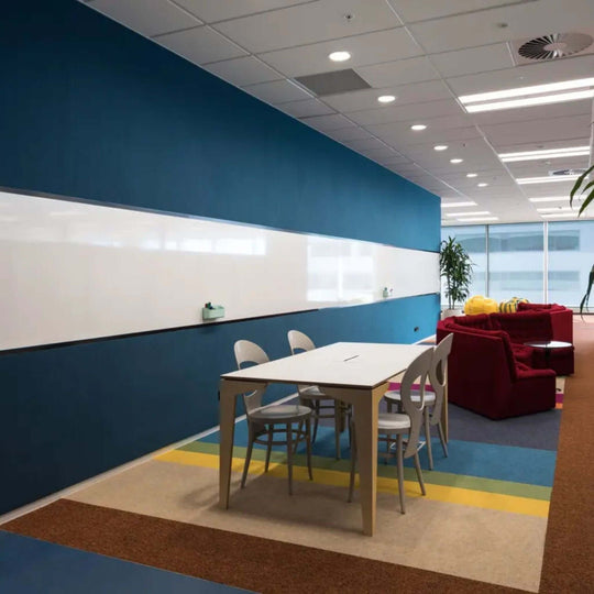 Modern office space featuring Autex Vertiface acoustic fabric wallcovering in blue, with a whiteboard and minimalist furniture.