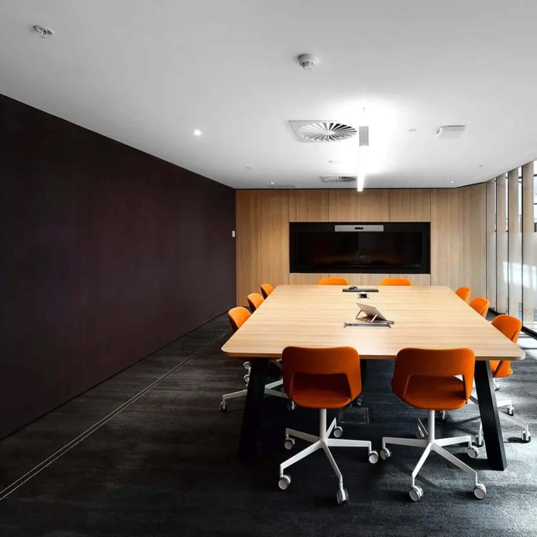 Modern conference room featuring a large wooden table and orange chairs, designed for collaborative meetings.