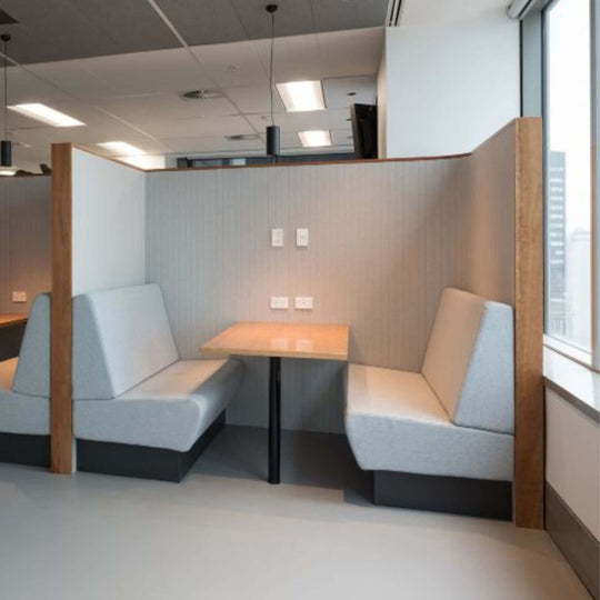 Modern acoustic booth with soft seating and wooden dividers in a contemporary office space.