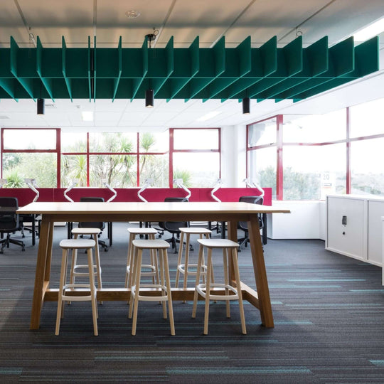 Autex Lattice™ acoustic baffles suspended above a modern office workspace with a communal table and stools.