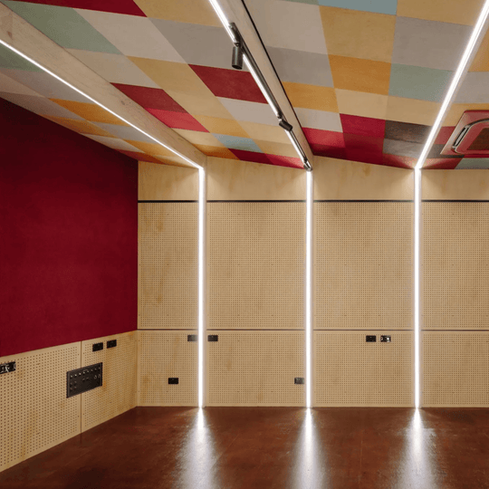 Vibrant room interior featuring Autex Composition® acoustic tiles in a colorful pattern and modern lighting design.