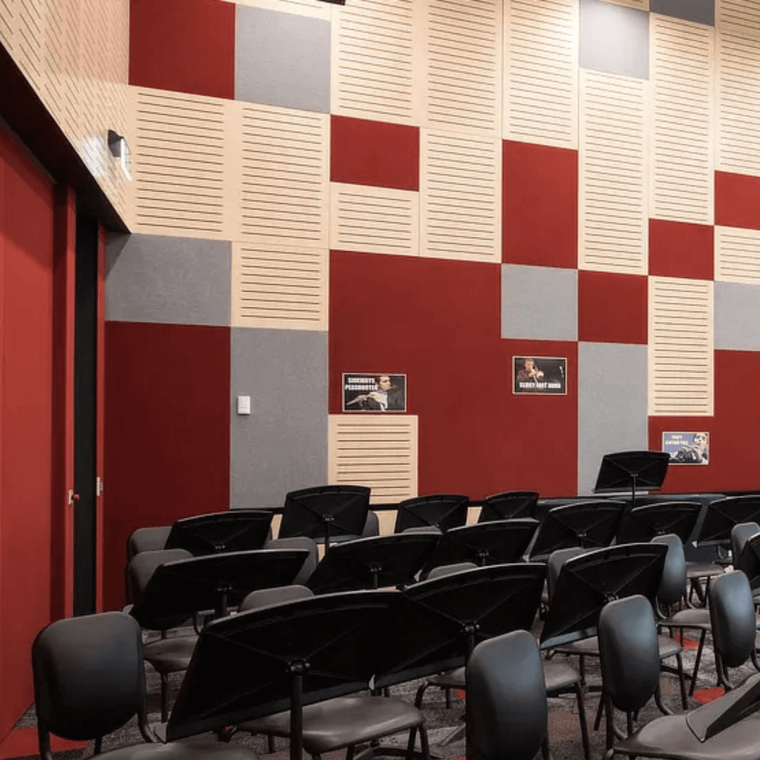 Colorful acoustic wall design featuring red, gray, and beige tiles in a music room with black chairs and posters.