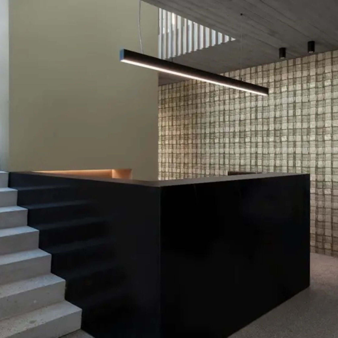 Modern interior featuring sleek black counter, illuminated by a contemporary hanging light fixture and textured wall.